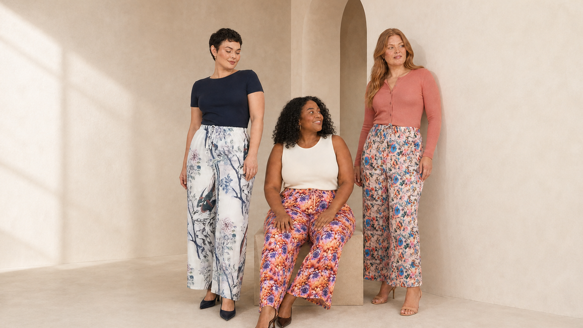 Three women styling porcelain blue, orange bloom and coral floral pleated wide-leg trousers in a warm cream studio.