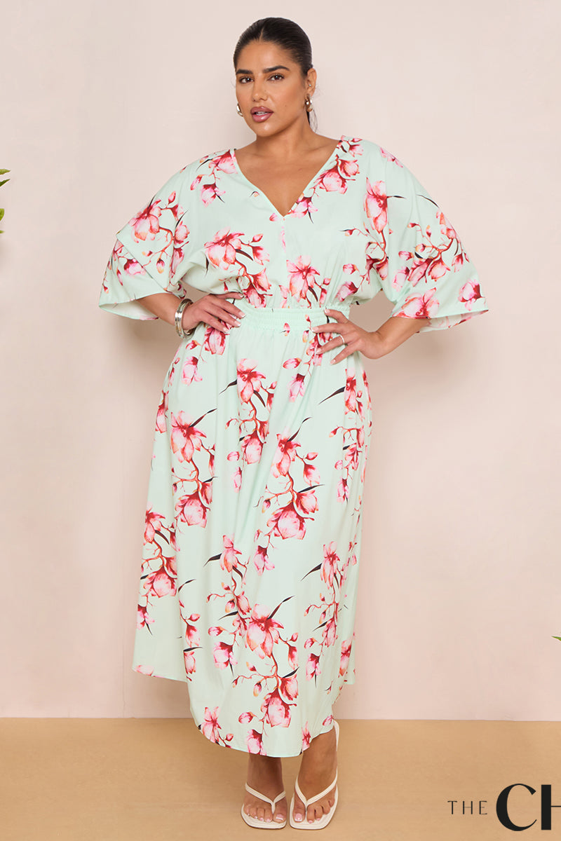 Woman wearing a floral dress with greenery on either side against a beige background, featuring 'The Chic Hero' brand.