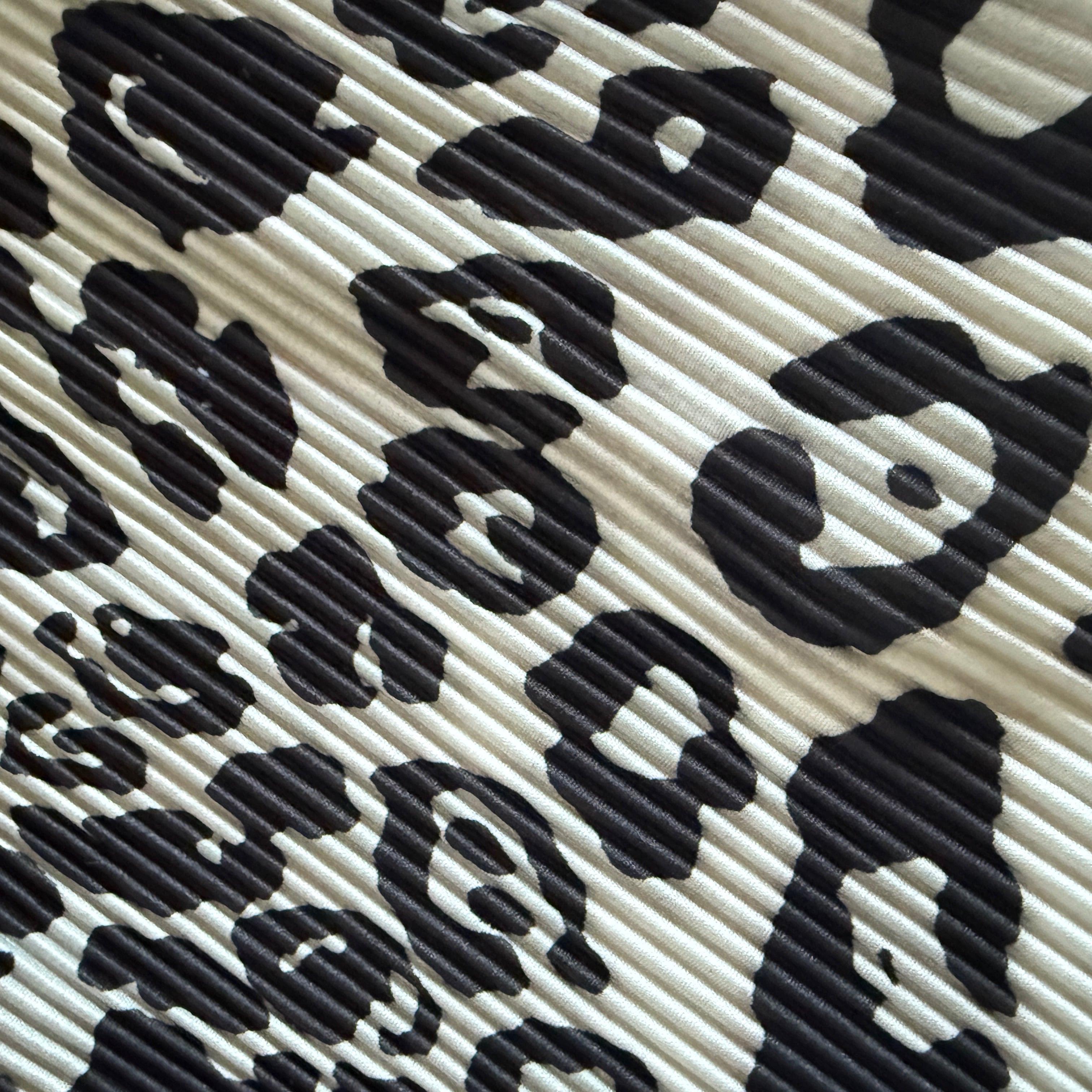 A close-up of a black and off-white leopard print fabric with a textured, ribbed surface.
