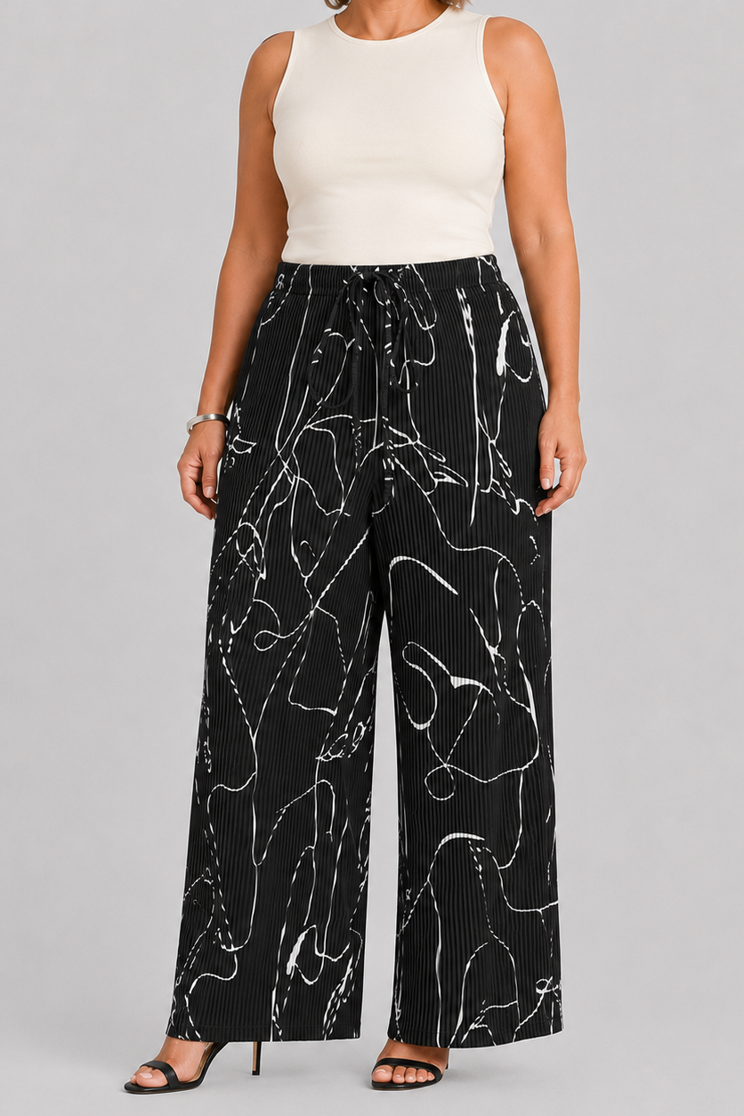 A model wearing black wide-leg pleated pants with a white abstract line pattern, paired with a cream sleeveless top, shown against a light gray studio background with 'THE CHIC HERO' text on the left.