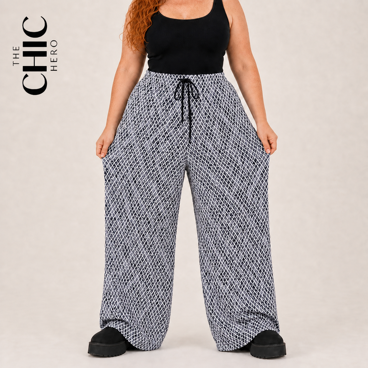 A model wearing wide-leg pants with a black and white geometric pattern, styled with a black tank top and black platform shoes. The brand logo 'THE CHIC HERO' is visible in the top left corner.