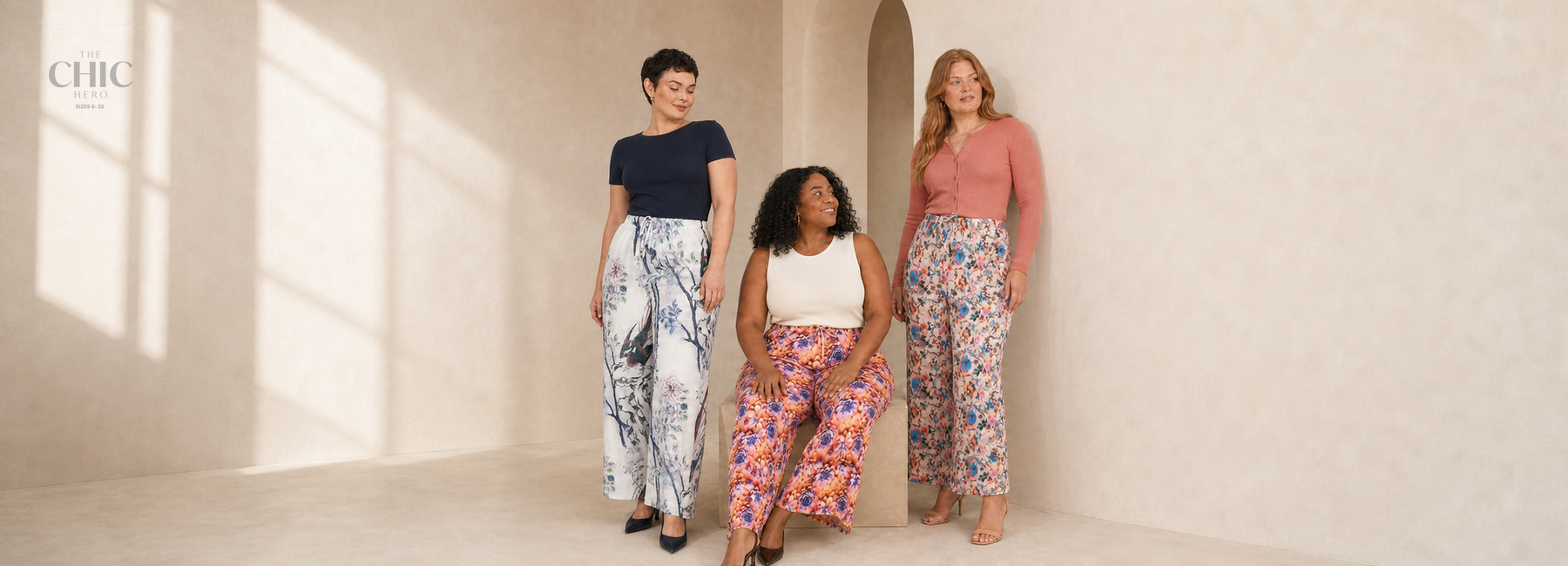 Three women styling porcelain blue, orange bloom and coral floral pleated wide-leg trousers in a warm cream studio.