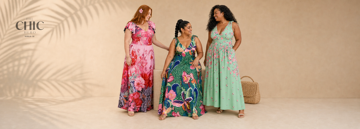 Three plus-size women wearing colourful floral one-piece swimsuits with coordinating long skirts in a warm summer studio