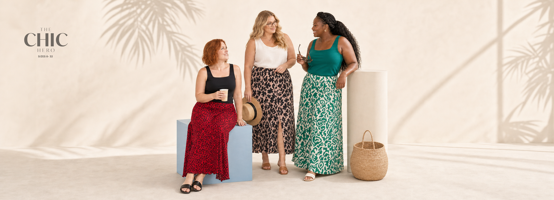 Three plus-size women wearing a red leopard skirt, a blush-and-black leaf skirt and a green printed maxi skirt in a bright summer studio.