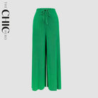 Plus size female model in green flowy high-waisted floral palazzo wide-leg trousers, stretchy opaque crease-resistant fabric, sizes UK 8–32