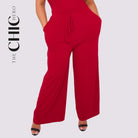 Red jumpsuit worn by a person on a light gray background with 'The Chic Hero' branding.