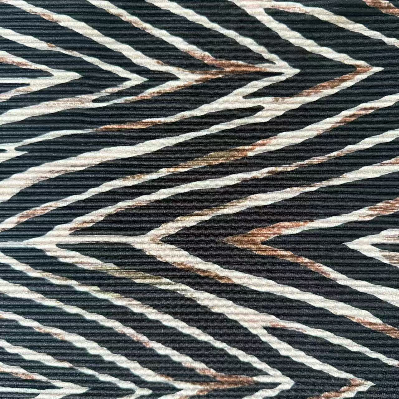 A close-up of a textured fabric featuring a bold chevron pattern in black, off-white, and brown.