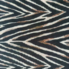 A close-up of a textured fabric featuring a bold chevron pattern in black, off-white, and brown.
