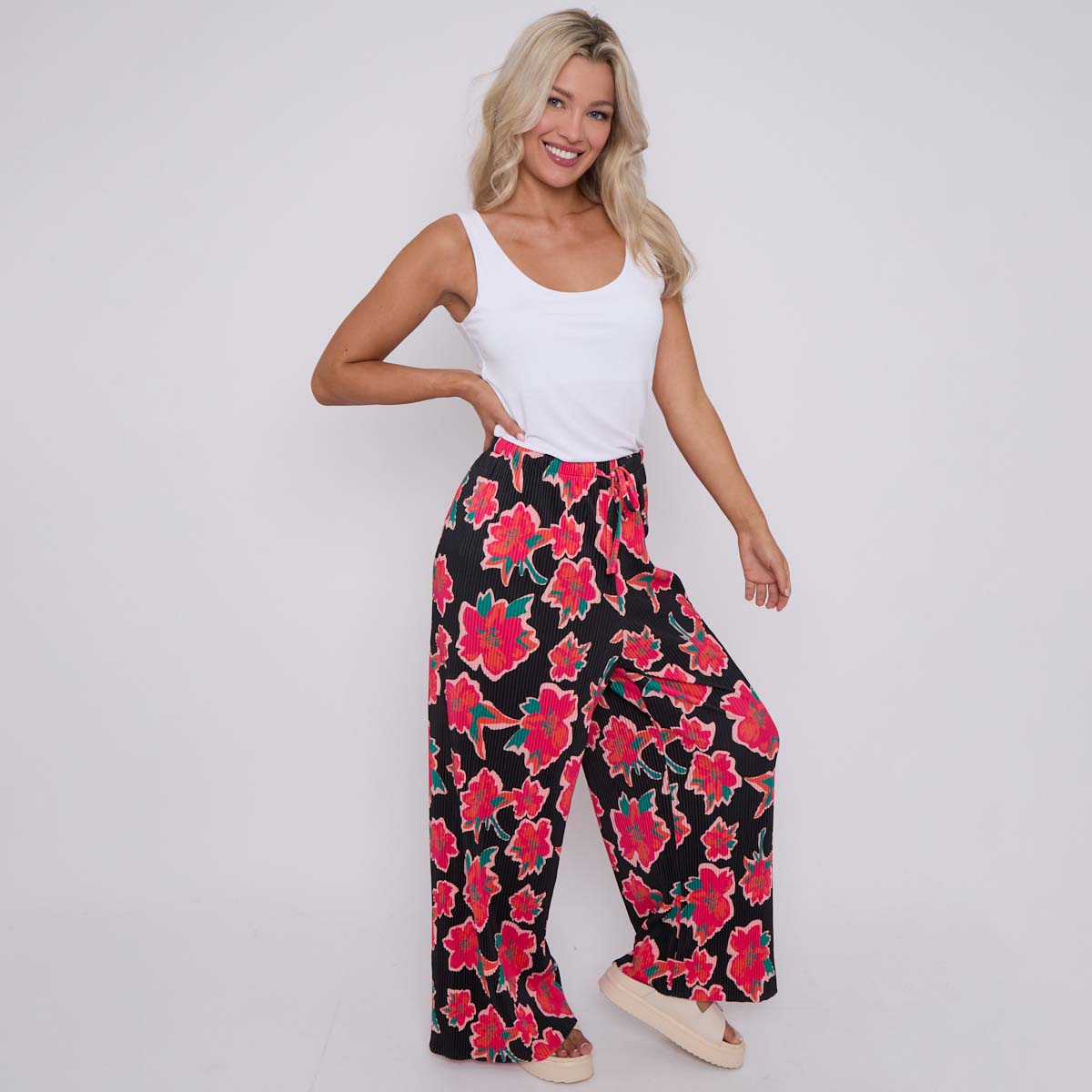 A model wearing wide-leg black palazzo pants with a floral abstract pattern in red and green.