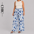 A model wearing wide-leg pants with a blue and white floral pattern, paired with a cream sleeveless top, shown against a solid gray background with 'THE CHIC HERO' text on the left.
