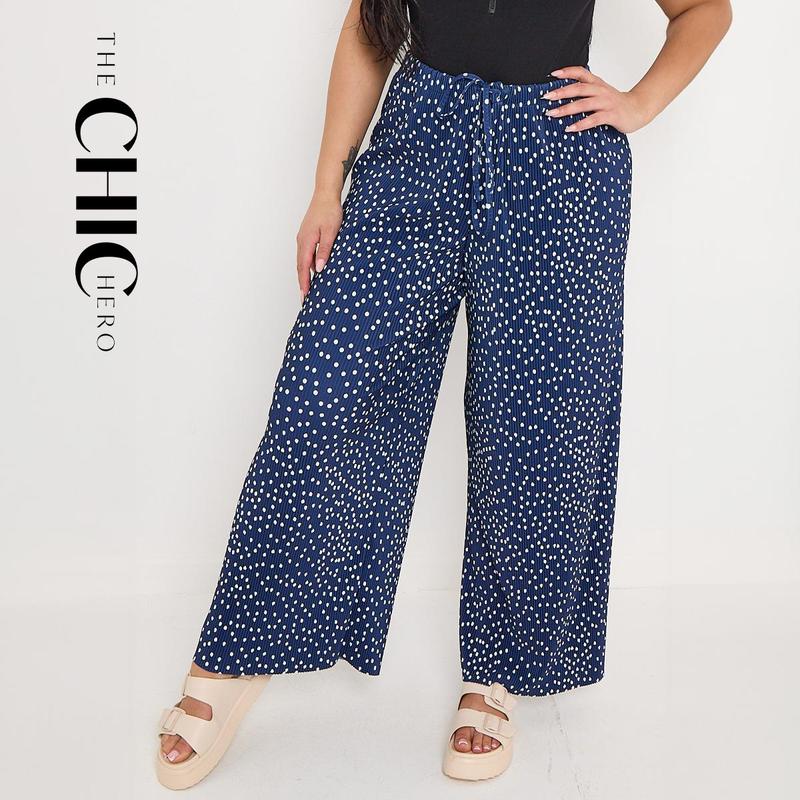 Plus size female model wearing blue polka dot print pleated palazzo pants, stretchy opaque crease-resistant fabric with drawstring waist, sizes UK 8–32