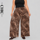 A model wearing wide-leg leopard print pants with a black tank top, shown from the chest down against a light gray studio background. The brand name 'THE CHIC HERO' is printed vertically on the left side.