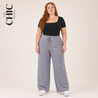 A woman modeling a black scoop-neck short-sleeve top and light gray wide-leg ribbed drawstring pants, standing against a plain beige studio background. The text 'THE CHIC HERO' appears in the upper left corner.