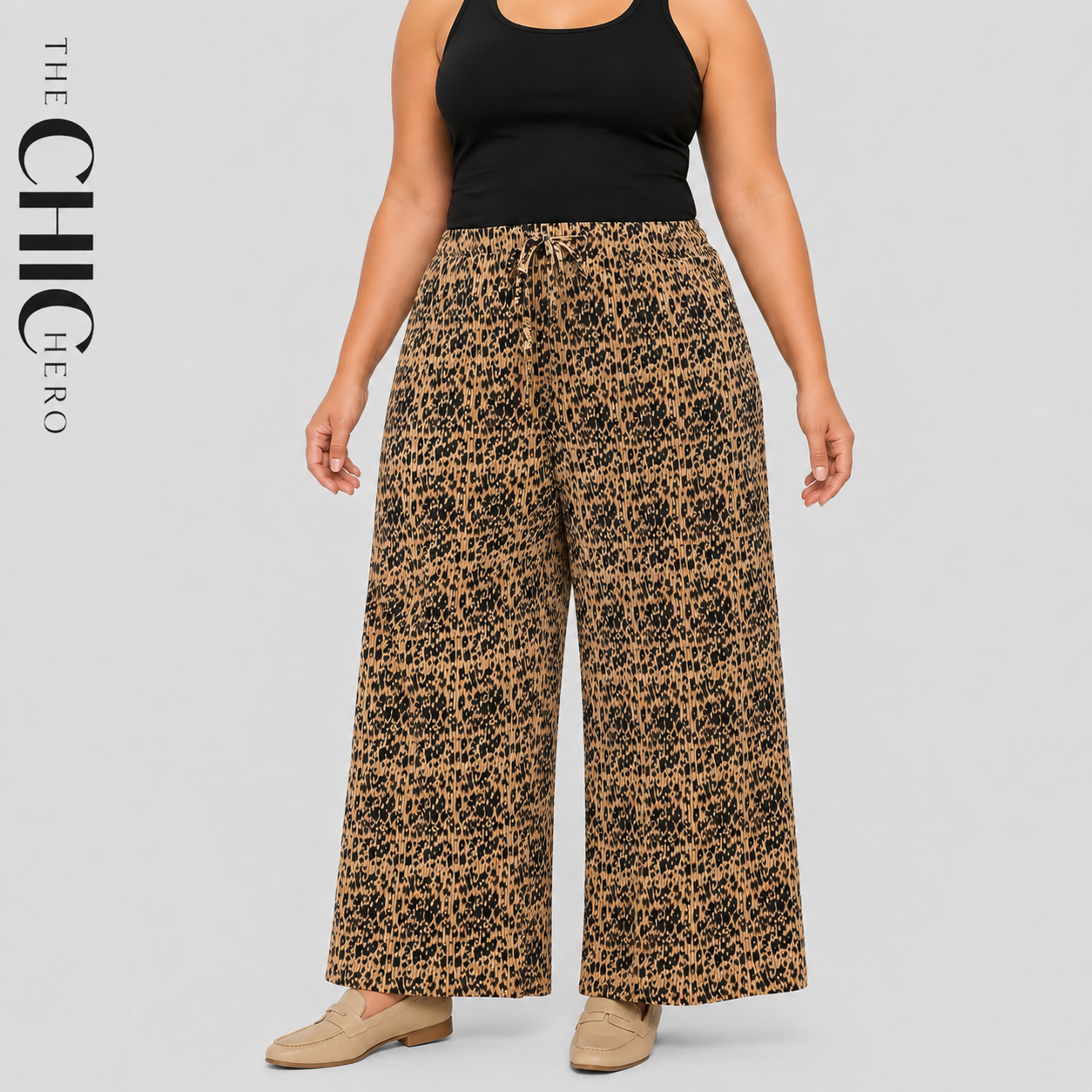A model wearing wide-leg pants with a brown and black leopard print pattern, styled with a black tank top and beige flat shoes against a light gray background. The brand logo 'THE CHIC HERO' is visible on the left side.