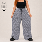 A model wearing wide-leg pants with a black and white geometric pattern, styled with a black tank top and black platform shoes. The brand logo 'THE CHIC HERO' is visible in the top left corner.